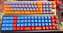 Two mechanical keyboards with colorful keycaps on a patterned surface